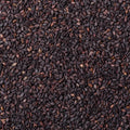 A close-up, top-down view of a dense pile of dark brown to black sesame seeds, filling the entire frame.