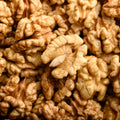 The photo is a detailed close-up featuring a multitude of shelled walnuts, their surfaces a mix of light and dark browns