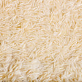 This eye-level close-up captures a sea of rice grains, filling the frame with their elongated shapes and creamy color. 