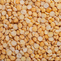 An overhead shot shows a pile of dried, yellow split peas on a mottled gray surface.