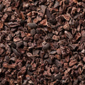 A close-up texture shot of dark brown cacao nibs or cocoa powder particles filling the entire frame.