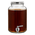 A large ribbed glass beverage dispenser filled with amber liquid, featuring a silver metal lid and a silver spout with a gray handle, isolated on a white background.