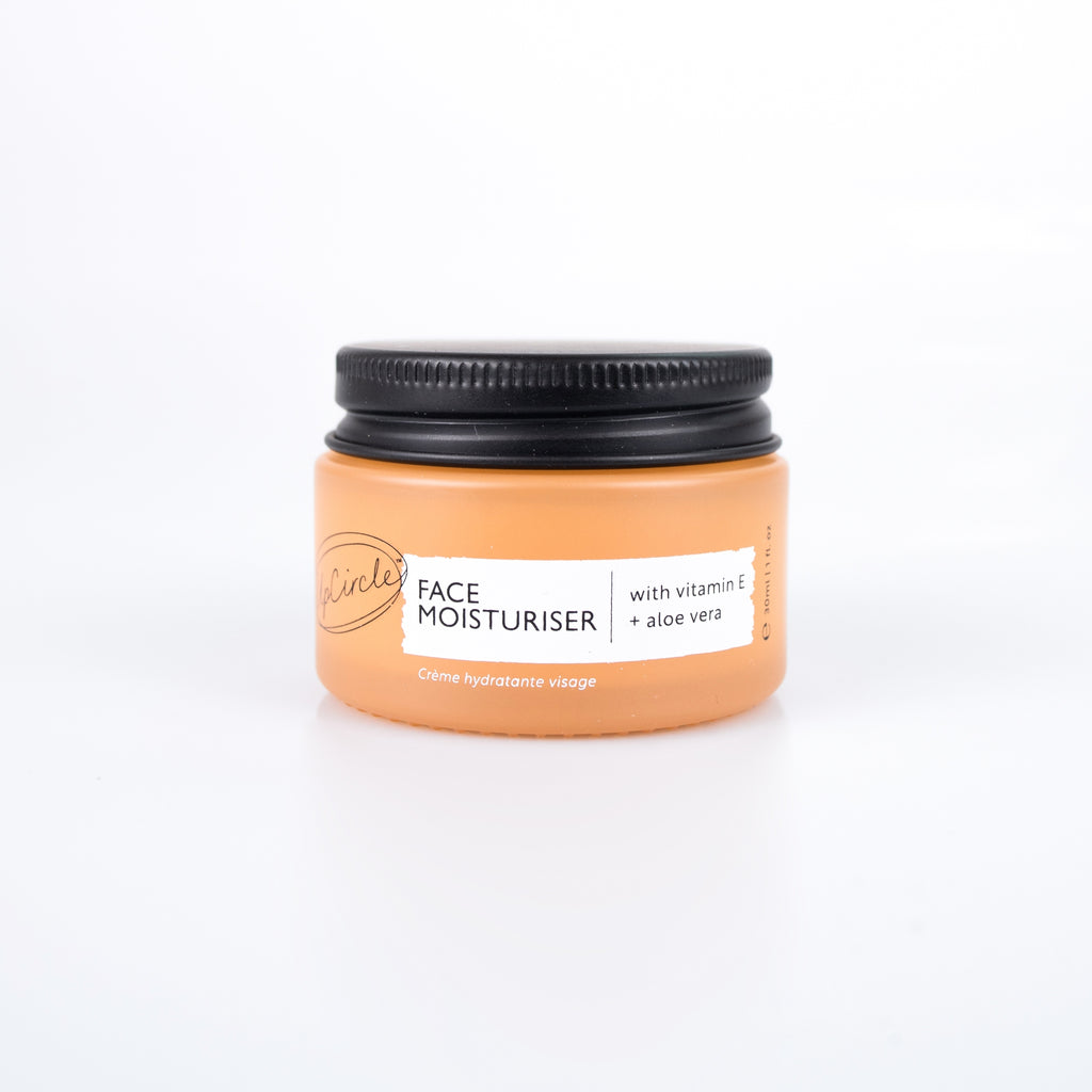 Jar of face moisturizer with a black lid on a white background