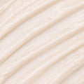 A close-up texture shot of a thick, creamy off-white cosmetic cream with diagonal ridges.