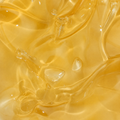 A close-up of a translucent golden yellow gel or liquid texture with glossy highlights and soft wavy contours.