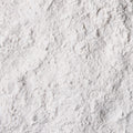 A close-up of a icing sugar, spread across a dark gray textured surface.
