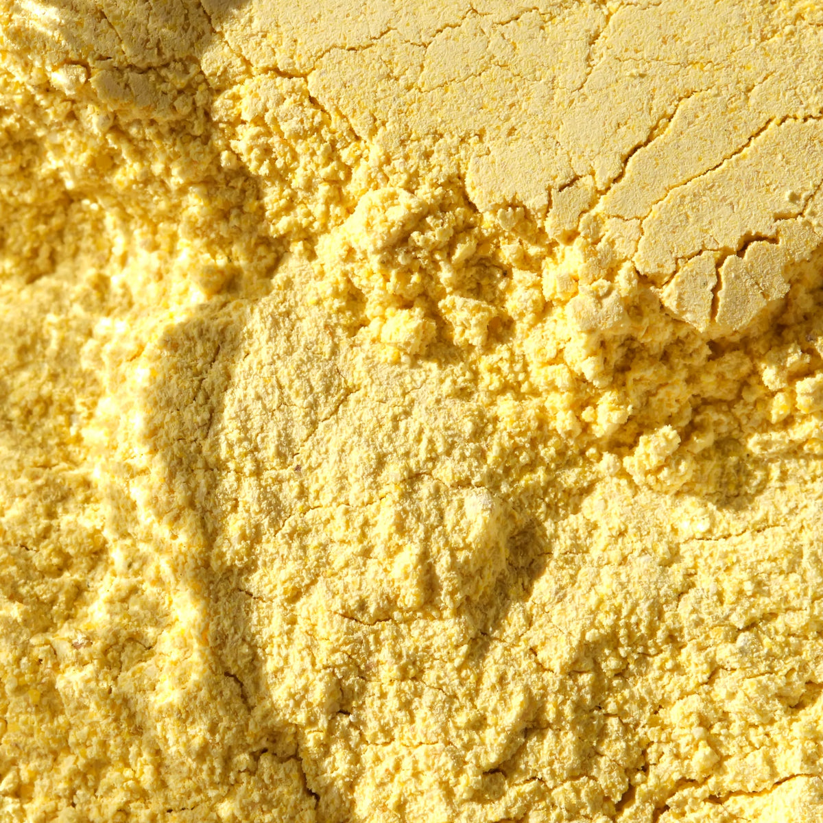 A close-up shot of bright yellow vegetable stock powder, filling the entire frame. 